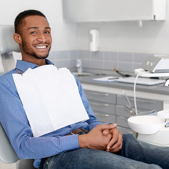 Man sitting in dental chair with his hands folded