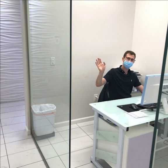 Dental team member waving from reception desk