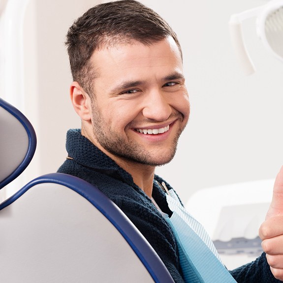 Male dental patient looking back and giving thumbs up