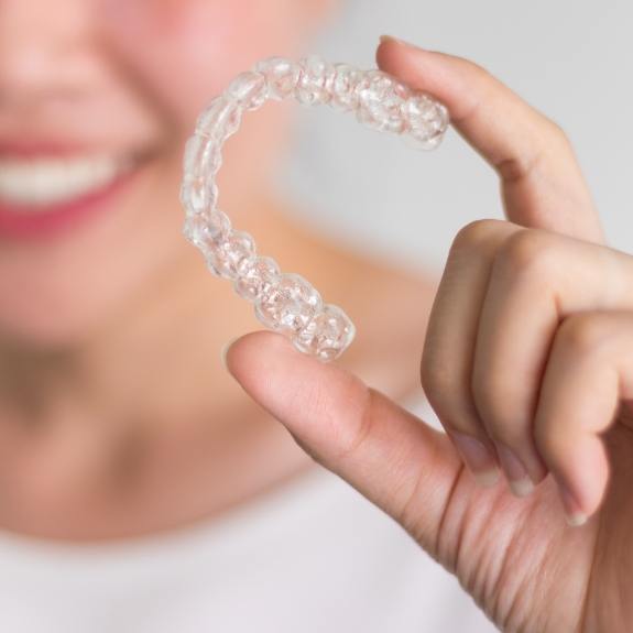 Dental patient holding an Invisalign clear braces tray