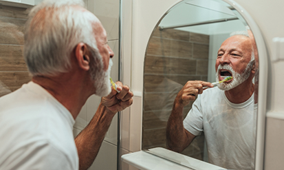 Senior man brushing his teeth at home