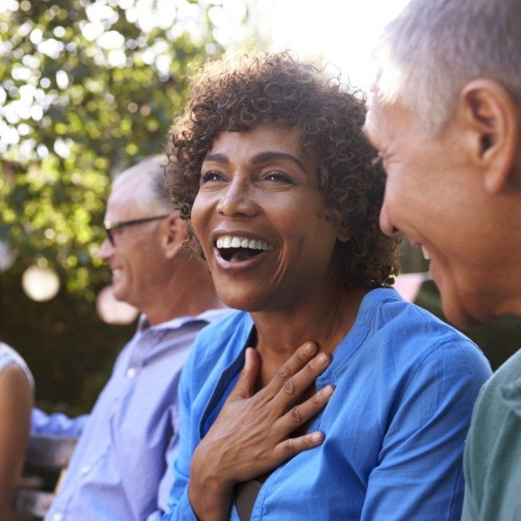 Group of older friends smiling together after tooth replacement with dental implants