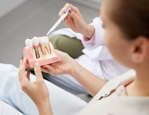 Dentist showing a patient a model of a dental implant