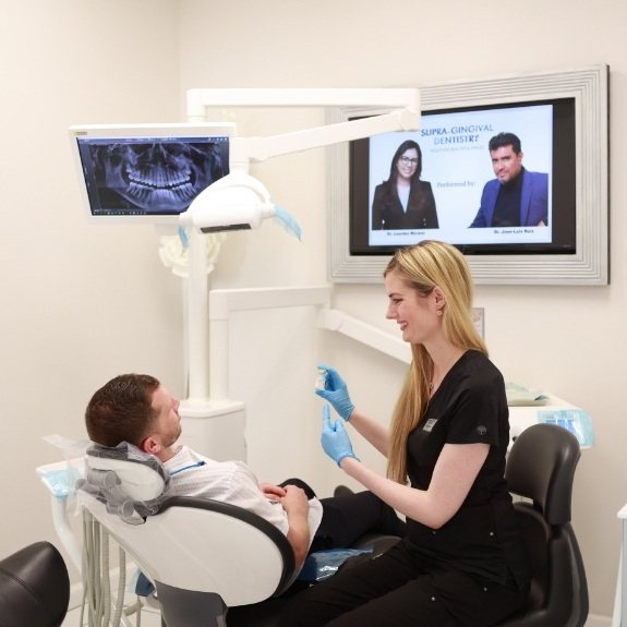 Dental team member talking to dentistry patient in dental treatment room