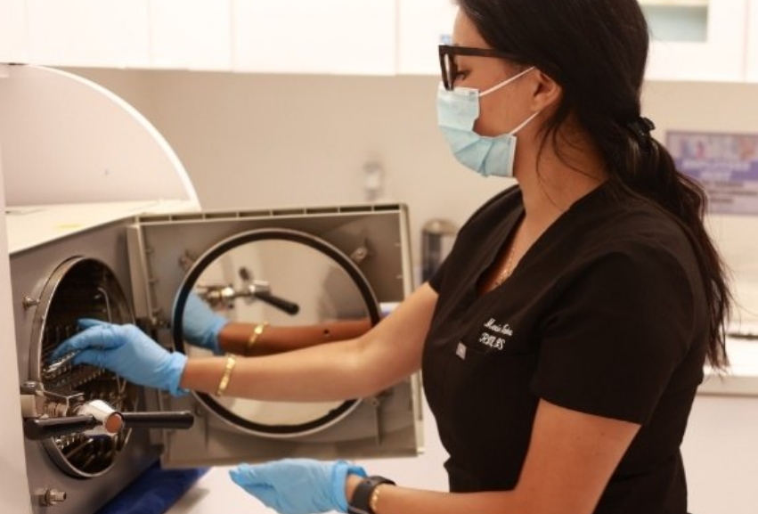 Dental team member reaching into a machine