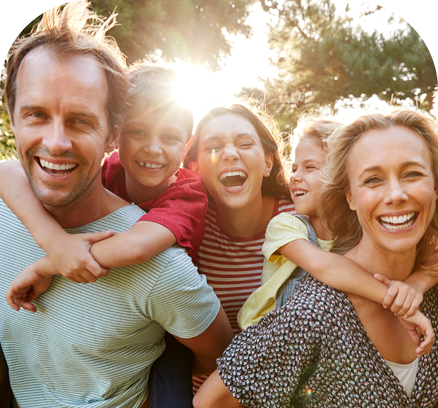 Family of five smiling in the sun after a preventive dental checkup