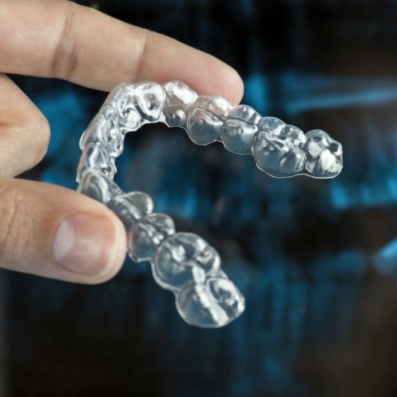 Hand holding clear nightguard for bruxism