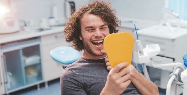 Man looking at healthy smile during preventive dentistry visit