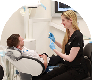 Dental team member showing a vial of medicine to a patient