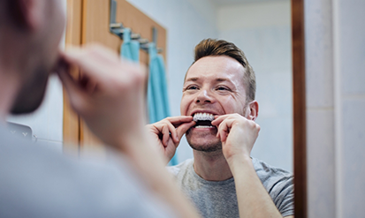 Man using a teeth whitening tray at home
