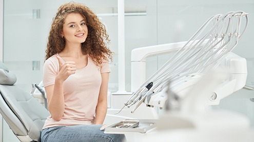Woman sitting in dental chair giving a thumbs up