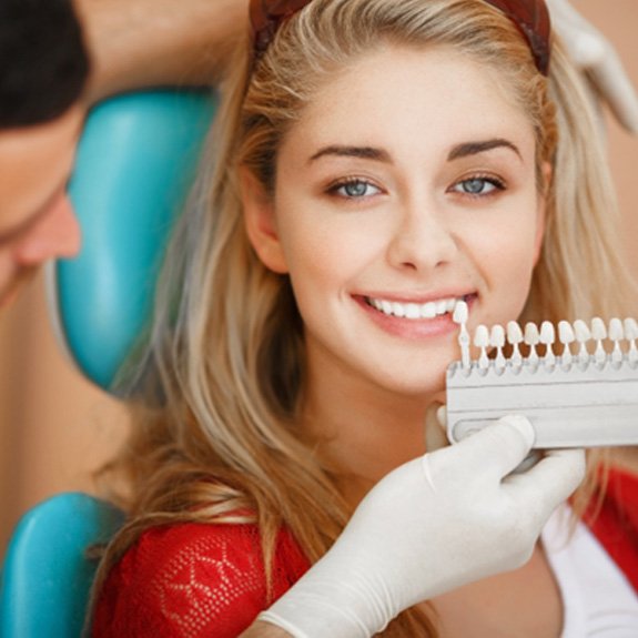 A dentist selecting the final tooth color for a patient’s teeth whitening