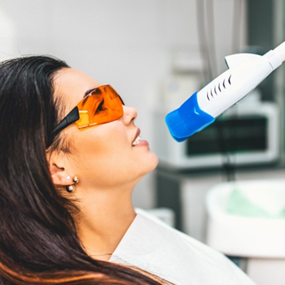 A woman receiving teeth whitening at a dental clinic