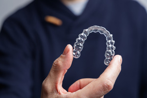 Close-up of man holding a single aligner for Invisalign