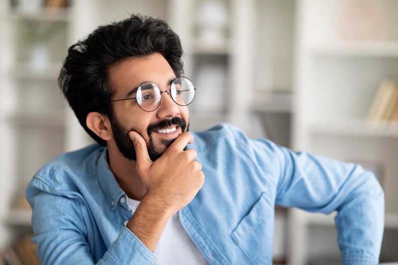 a man smiling and thinking while looking out the window