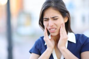 Woman holding jaw in pain. 